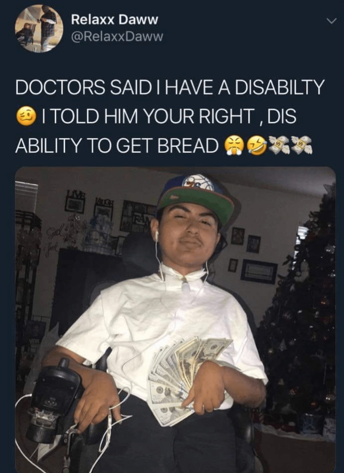 A meme from @RelaxDaww. There is text above a photograph. The text reads “DOCTORS SAID I HAVE A DISABILITY (cringe emoji) I TOLD HIM YOUR [sic] RIGHT, DIS ABILITY TO GET BREAD (steam coming out of nose emoji)(crying laughing emoji)(two money with wings emojis). The photograph shows a person with brown hair and brown skin wearing a cap, a white shirt and black trousers. They are holding a stack of dollar bills in their hand. They are sitting in an electric wheelchair. Their chin is lifted and they are smirking as if to say “and what??”. They are in what looks like a home environment with pictures hanging on the wall and a christmas tree in the background.  
